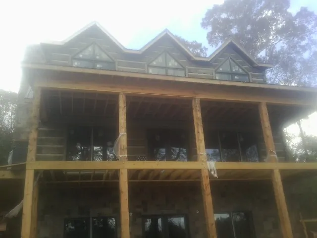 Dormers and porch framing on a large log home under construction — Roof Coating work by our crew in Crofton